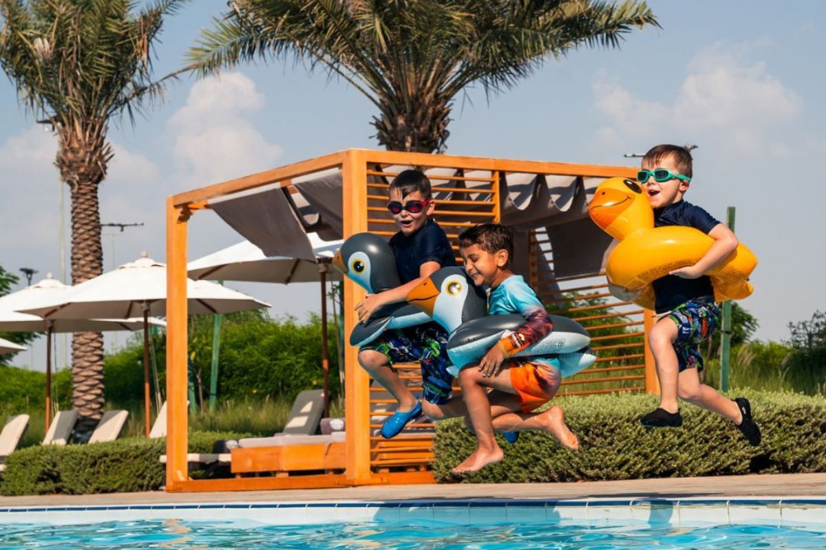 Yas Acres Golf and Country club summer offers 2024 3 little boys jumping on the pool with their floaties at Yas ACres Golf and Country Club summer offers 2024