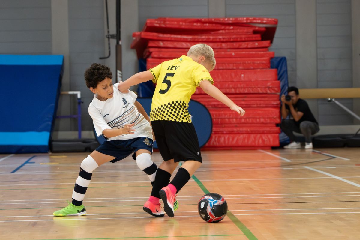 Abu Dhabi futsal leagues finals this weekend (2) 2 kids from the opposing team battling it out playing football at Abu Dhabi futsal leagues finals this weekend
