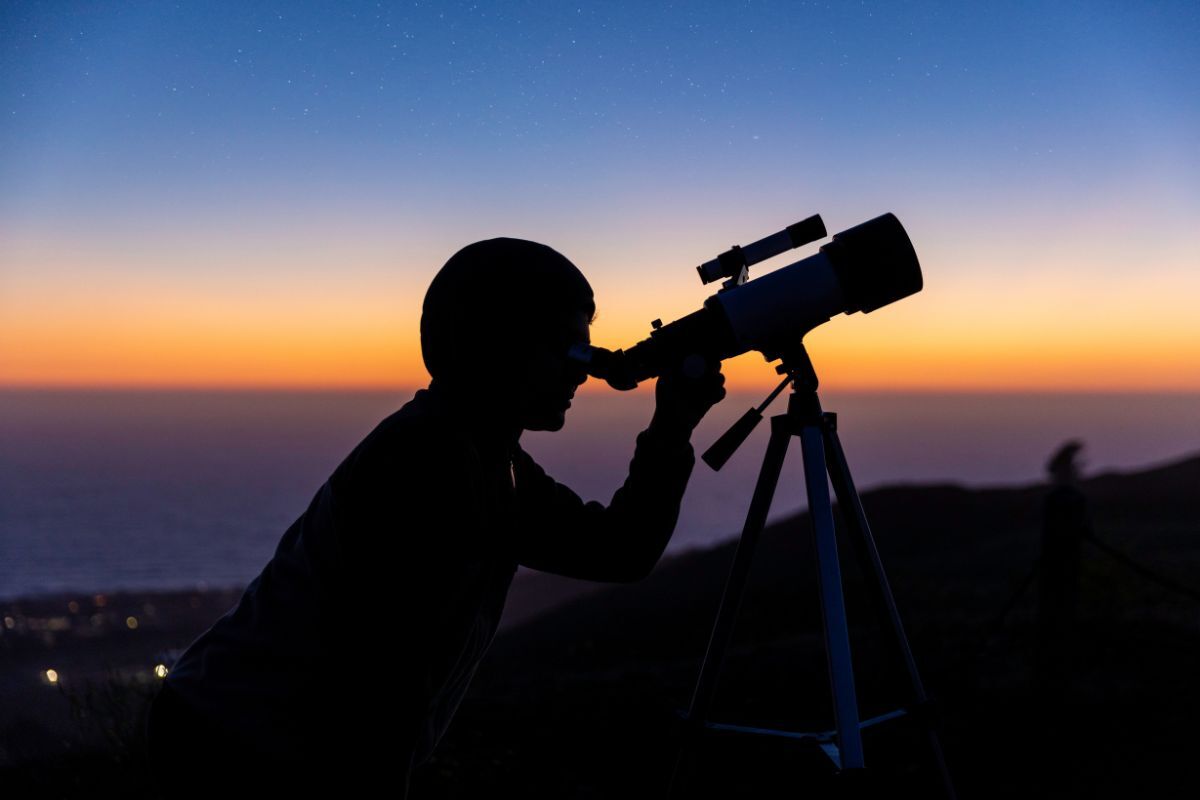 Supermoon gazing A silhouette of a person holding up a telescope during stargazing