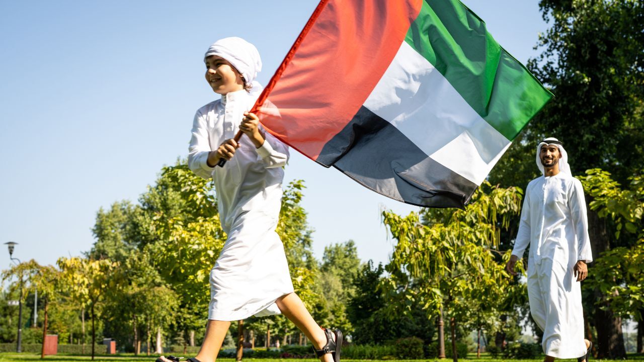 eid al etihad kid running in the park with UAE flag