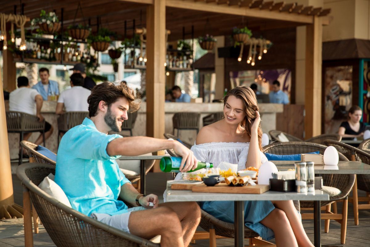Saadiyat Rotana outdoor seating (2) Nasma Beachfront at Saadiyat Rotana Resorts and Villas outdoor seating, a couple enjoying meals and the guy pouring sparkling water onto glasses